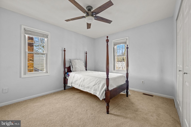 bedroom featuring visible vents, baseboards, ceiling fan, a closet, and light colored carpet