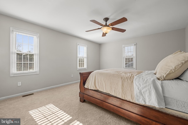 carpeted bedroom featuring visible vents, a ceiling fan, and baseboards