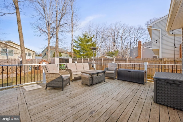 wooden terrace with an outbuilding, a shed, an outdoor living space, and a fenced backyard