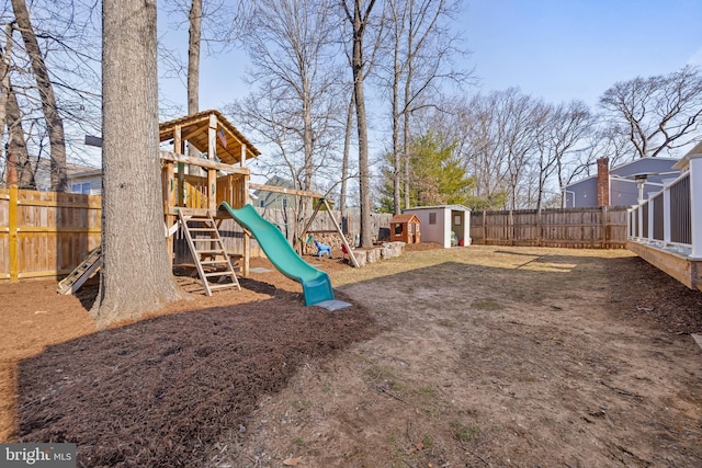 view of playground with an outbuilding, a fenced backyard, and a shed