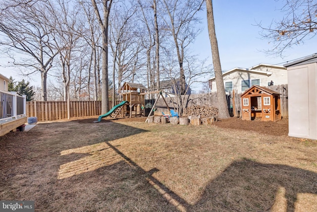 view of yard featuring an outbuilding, a playground, and a fenced backyard