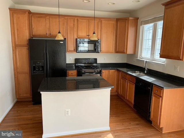 kitchen featuring black appliances, a kitchen island, a sink, and light wood-style flooring