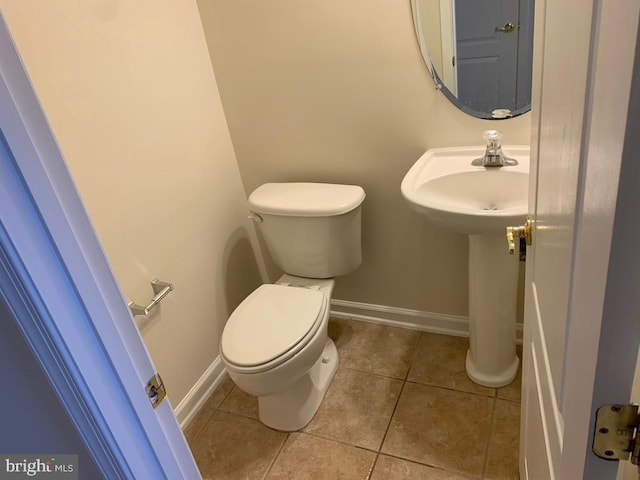 bathroom with tile patterned flooring, baseboards, and toilet