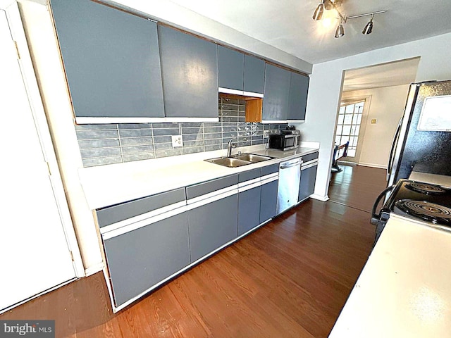 kitchen with tasteful backsplash, dark wood finished floors, light countertops, black appliances, and a sink