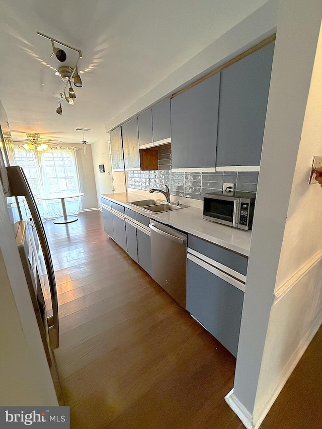 kitchen featuring decorative backsplash, appliances with stainless steel finishes, dark wood-style flooring, light countertops, and a sink