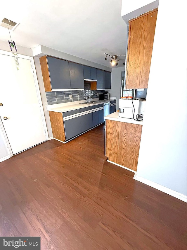 kitchen with dark wood-style flooring, visible vents, light countertops, backsplash, and a sink