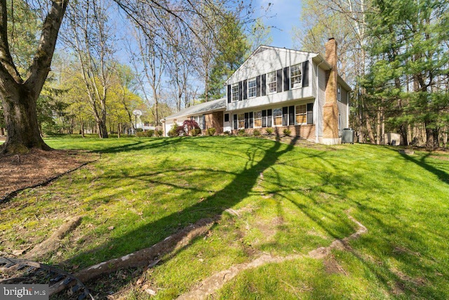 view of front of home featuring central AC, brick siding, a chimney, and a front yard