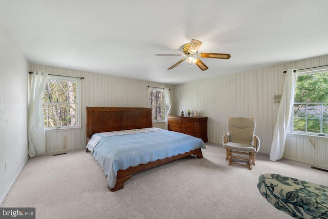 carpeted bedroom featuring visible vents, ceiling fan, and multiple windows