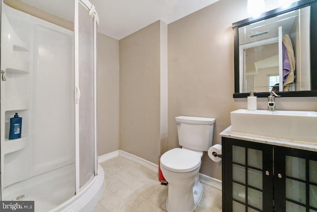 full bath featuring toilet, vanity, baseboards, a shower stall, and tile patterned floors