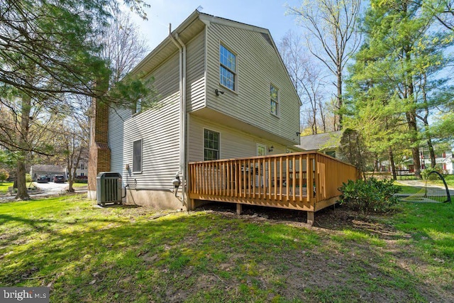 back of house featuring central AC, a lawn, and a wooden deck