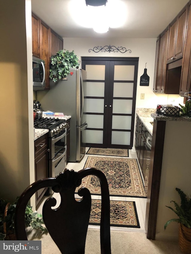 kitchen with dark brown cabinetry, light stone countertops, and appliances with stainless steel finishes