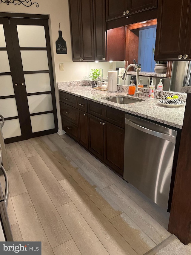 kitchen with a sink, stainless steel dishwasher, dark brown cabinets, and light wood finished floors