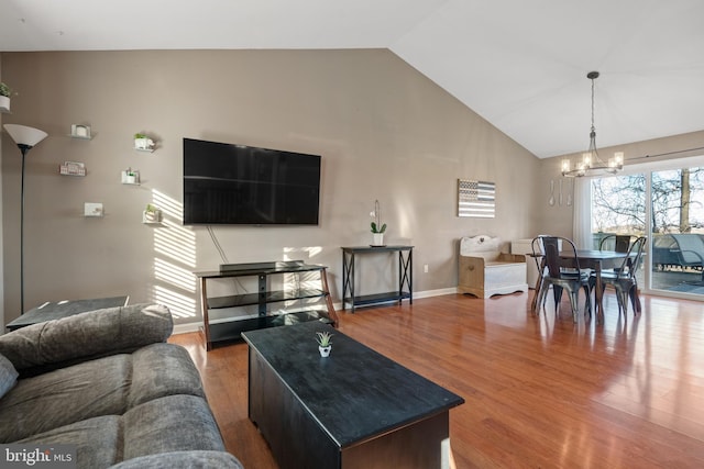 living room featuring a notable chandelier, high vaulted ceiling, baseboards, and wood finished floors