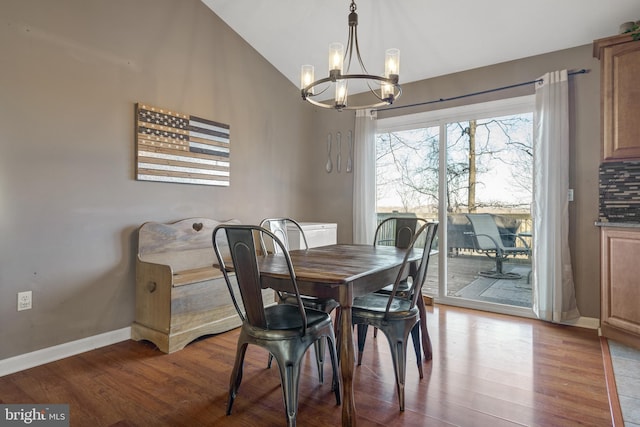 dining space with an inviting chandelier, vaulted ceiling, wood finished floors, and baseboards