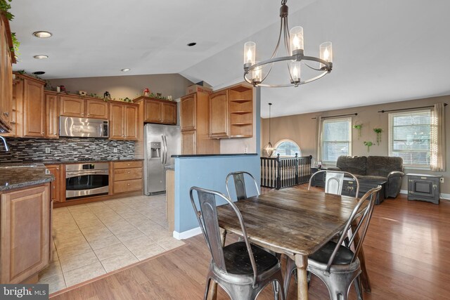 dining room featuring lofted ceiling, a notable chandelier, baseboards, and light wood-type flooring