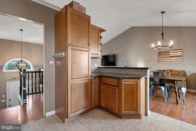 kitchen with light tile patterned floors, a peninsula, a chandelier, and vaulted ceiling