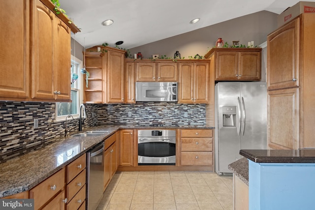 kitchen with light tile patterned floors, dark stone counters, a sink, stainless steel appliances, and vaulted ceiling