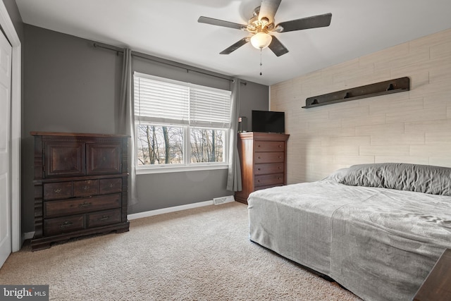 carpeted bedroom with visible vents, baseboards, ceiling fan, and an accent wall