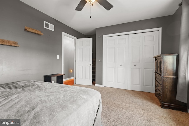 carpeted bedroom with a closet, visible vents, baseboards, and ceiling fan