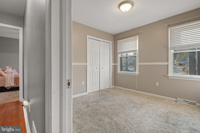 unfurnished bedroom with carpet flooring, baseboards, visible vents, and a closet