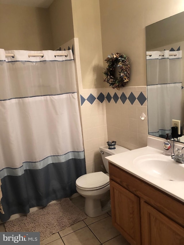 full bath featuring toilet, a shower with curtain, tile patterned floors, vanity, and tile walls