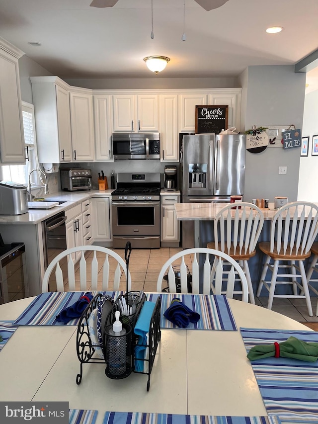 kitchen featuring white cabinets, stainless steel appliances, a sink, and light countertops