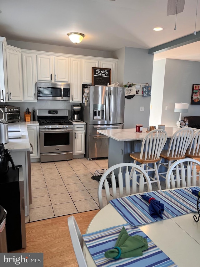 kitchen featuring light tile patterned floors, white cabinetry, stainless steel appliances, and light countertops