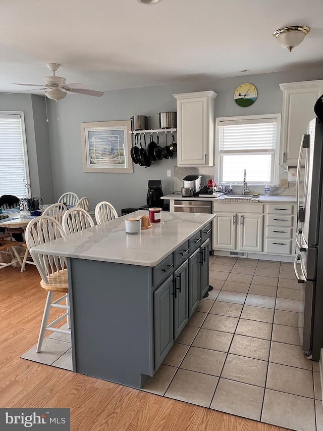 kitchen featuring a breakfast bar, stainless steel appliances, light countertops, white cabinets, and a sink