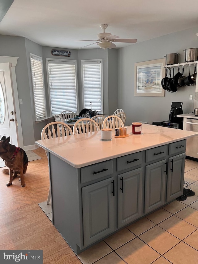 kitchen with a center island, gray cabinets, light countertops, dishwasher, and a kitchen breakfast bar