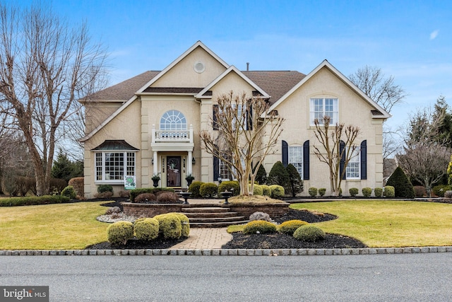 view of front of property featuring a shingled roof, a front yard, and stucco siding