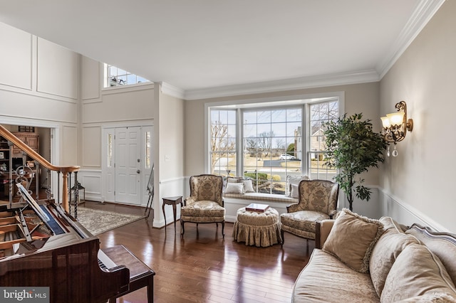 living area featuring crown molding, a decorative wall, hardwood / wood-style floors, and stairs