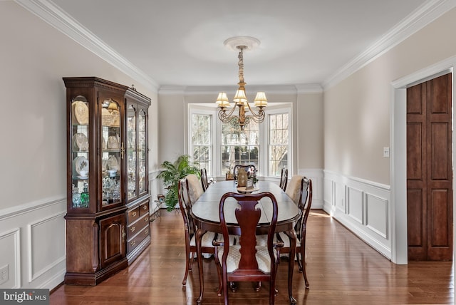 dining room with a decorative wall, wainscoting, an inviting chandelier, dark wood finished floors, and crown molding