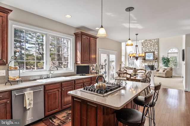 kitchen featuring light stone counters, stainless steel appliances, a breakfast bar, a kitchen island, and a sink