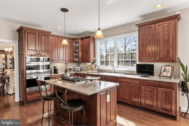 kitchen with decorative backsplash, a breakfast bar area, wood finished floors, stainless steel appliances, and a sink