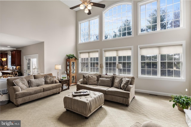 living room featuring a high ceiling, light carpet, plenty of natural light, and baseboards