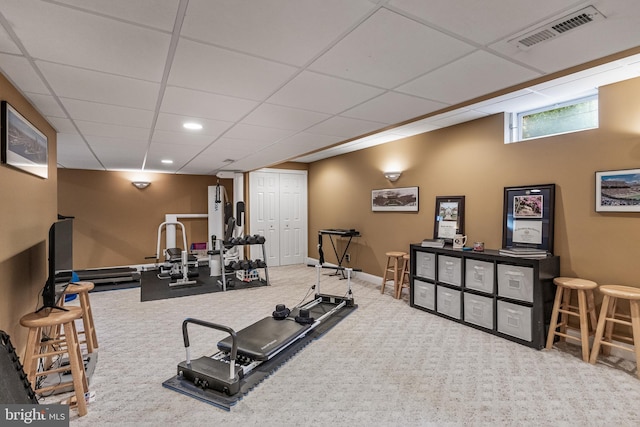 workout area featuring baseboards, visible vents, a drop ceiling, and carpet flooring