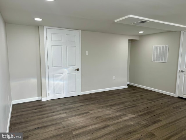 basement featuring dark wood-style floors, baseboards, and visible vents