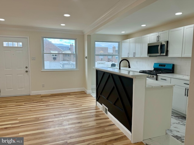 kitchen featuring plenty of natural light, appliances with stainless steel finishes, light countertops, crown molding, and backsplash