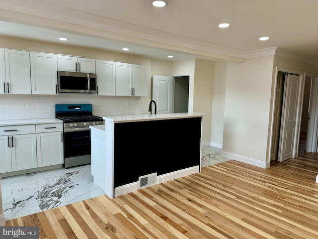 kitchen featuring visible vents, decorative backsplash, appliances with stainless steel finishes, ornamental molding, and light countertops