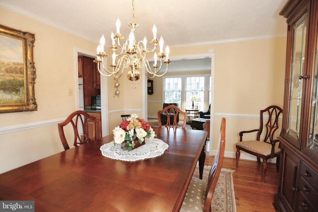 dining area featuring a notable chandelier, crown molding, and wood finished floors