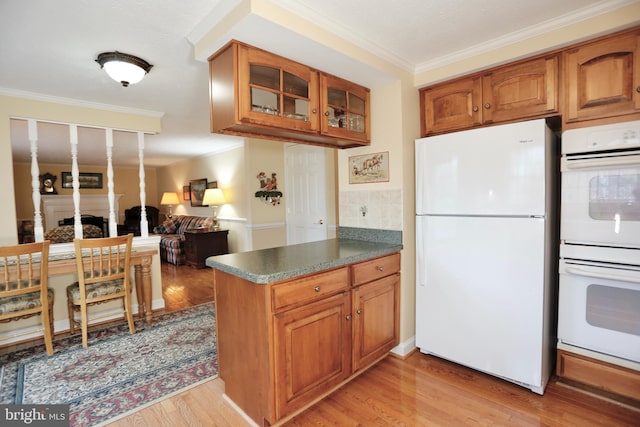 kitchen featuring light wood-style flooring, white appliances, brown cabinets, glass insert cabinets, and crown molding