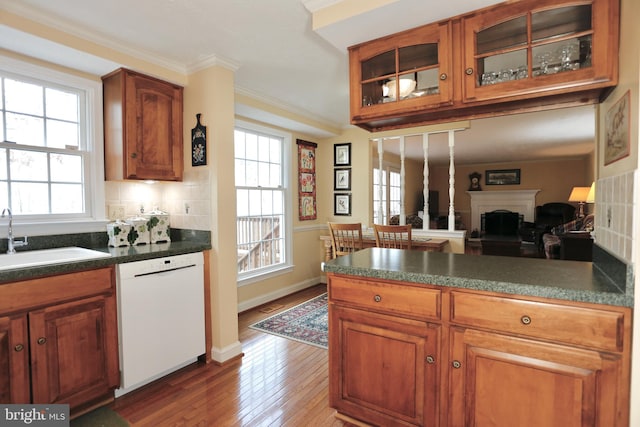 kitchen with crown molding, brown cabinetry, glass insert cabinets, a sink, and dishwasher