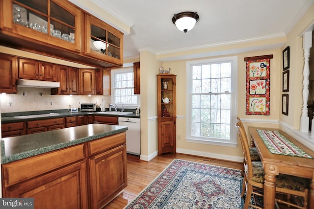 kitchen featuring under cabinet range hood, white appliances, a sink, ornamental molding, and tasteful backsplash