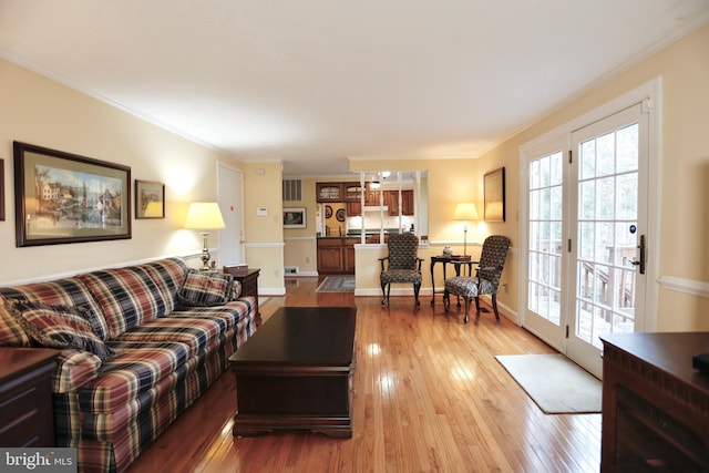 living room with hardwood / wood-style flooring, baseboards, and ornamental molding