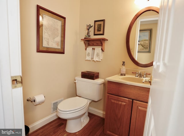 bathroom featuring visible vents, toilet, vanity, wood finished floors, and baseboards