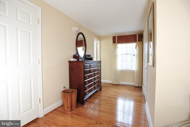 corridor featuring baseboards and wood finished floors