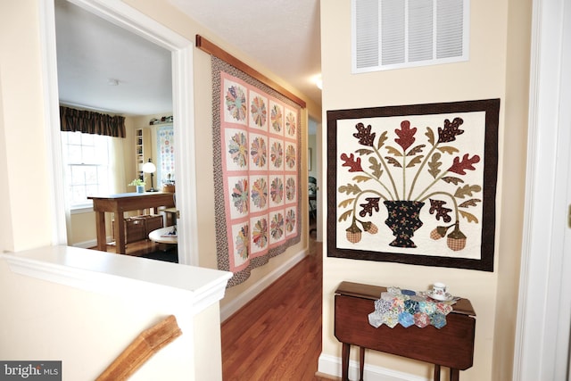 hallway with visible vents, baseboards, and wood finished floors