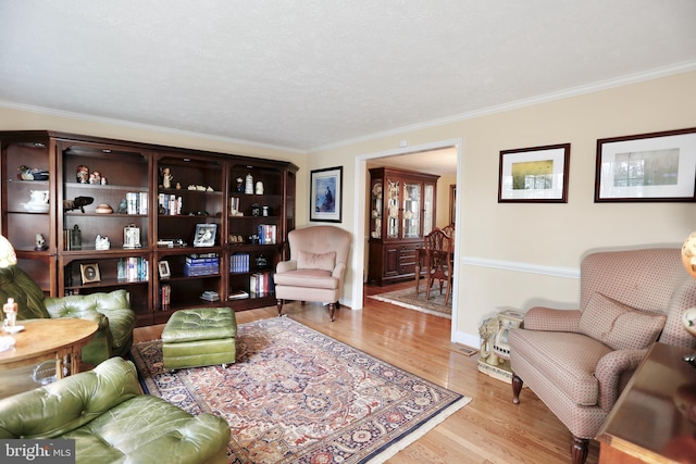 living area featuring baseboards, crown molding, and light wood finished floors