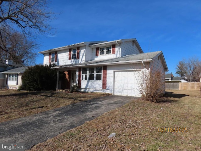 traditional home with a garage, aphalt driveway, and fence