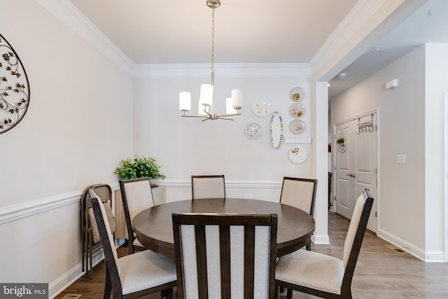 dining room with baseboards, crown molding, an inviting chandelier, and wood finished floors